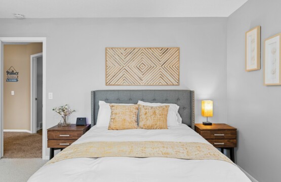 a bedroom with a neatly made bed and a painting on the wall